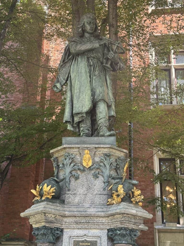 Bronze statue of Copernicus holding an astrolabe outside Jagiellonian University in Krakow, with historic building backdrop